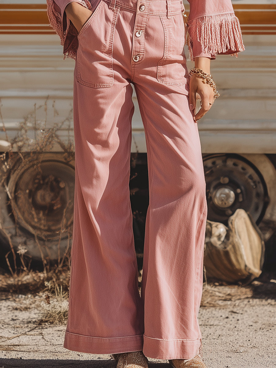 Combinaison rétro western rose avec manches longues, jambes larges et franges.